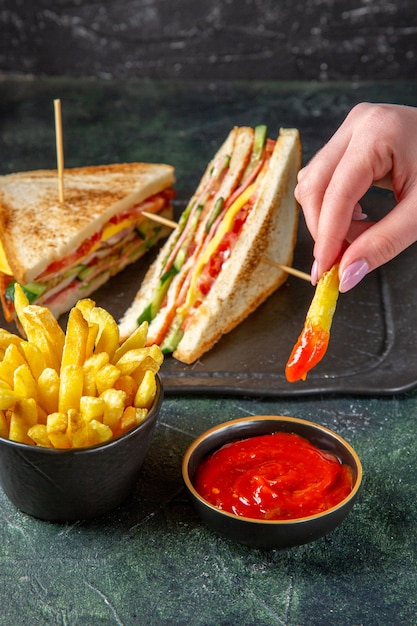 Vue avant de savoureux sandwichs au jambon avec frites surface sombre