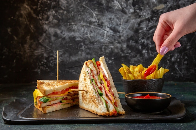 Vue avant de savoureux sandwichs au jambon avec frites surface sombre