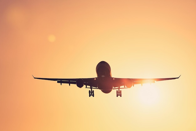 Vue à bas angle de l'avion de silhouette contre un ciel clair au coucher du soleil