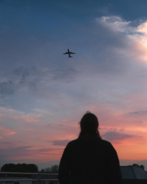 Photo vue à bas angle de l'avion en silhouette et de la femme contre le ciel au coucher du soleil