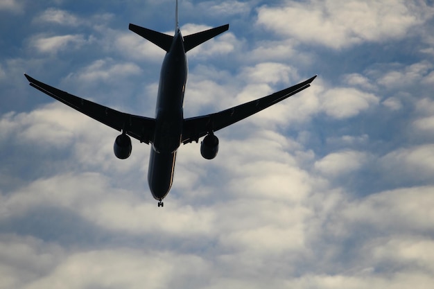 Vue à bas angle d'un avion en silhouette volant contre un ciel nuageux