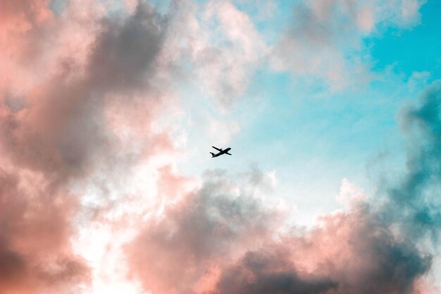 Photo vue à bas angle d'un avion de silhouette volant dans le ciel au coucher du soleil