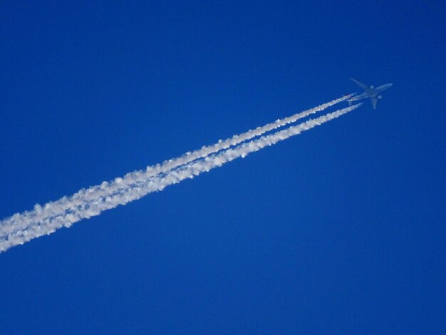 Photo vue à bas angle d'un avion volant contre un ciel bleu clair