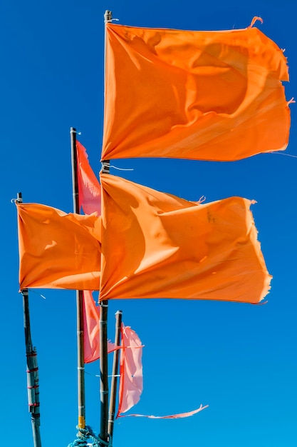 Vue à bas angle des drapeaux orange agitant contre un ciel bleu clair
