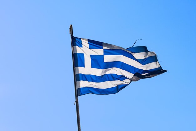 Vue en bas angle du drapeau grec sur un ciel bleu clair