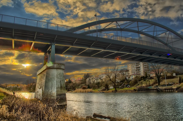 Vue à bas angle du pont sur la rivière au coucher du soleil