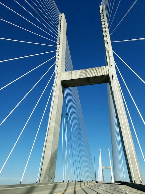 Photo vue à bas angle du pont suspendu contre un ciel bleu clair