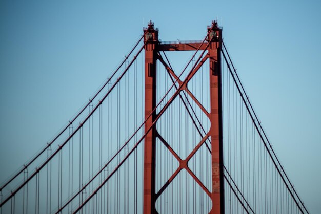 Photo vue à bas angle du pont suspendu contre un ciel bleu clair