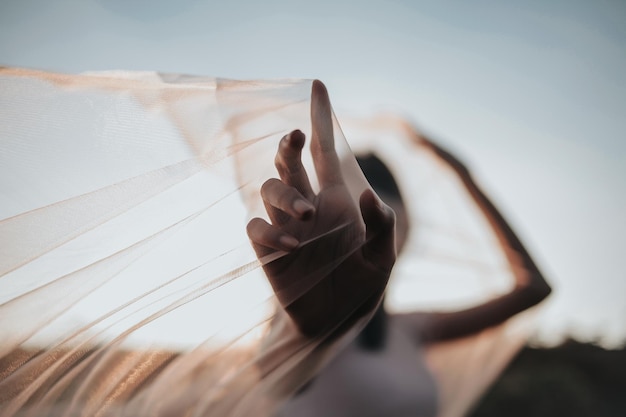 Vue à bas angle d'une femme tenant un foulard contre le ciel au coucher du soleil