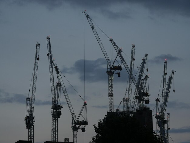 Photo vue à bas angle des grues sur le chantier contre un ciel nuageux