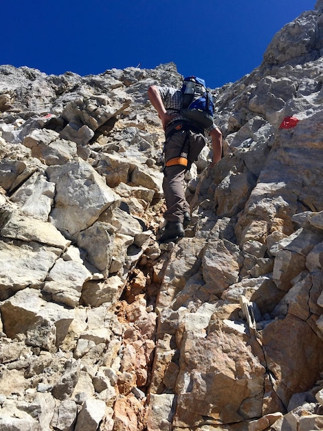 Photo vue à bas angle d'un homme grimpant sur une formation rocheuse