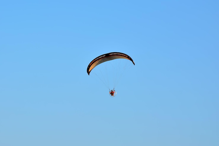 Photo vue à bas angle d'un homme en parapente contre le ciel bleu