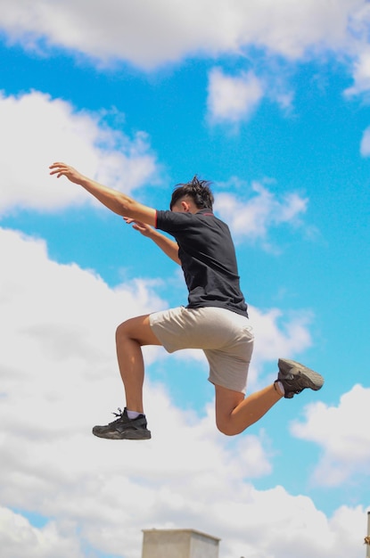 Vue à bas angle d'un homme sautant contre un ciel nuageux