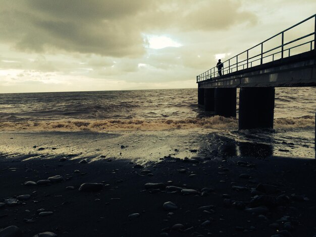 Photo vue à bas angle de la jetée sur la plage contre un ciel nuageux