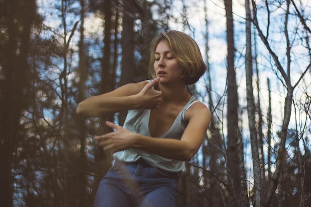 Vue à bas angle d'une jeune femme dansant dans la forêt