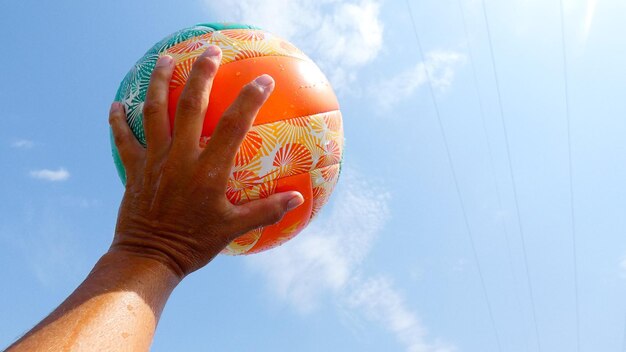 Vue en bas angle de la main tenant le ballon contre le ciel