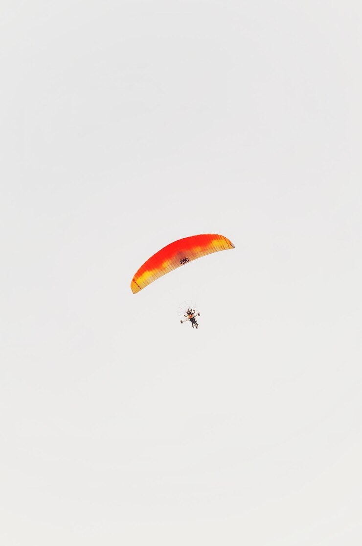 Photo vue à bas angle d'une personne en parapente contre un ciel clair.