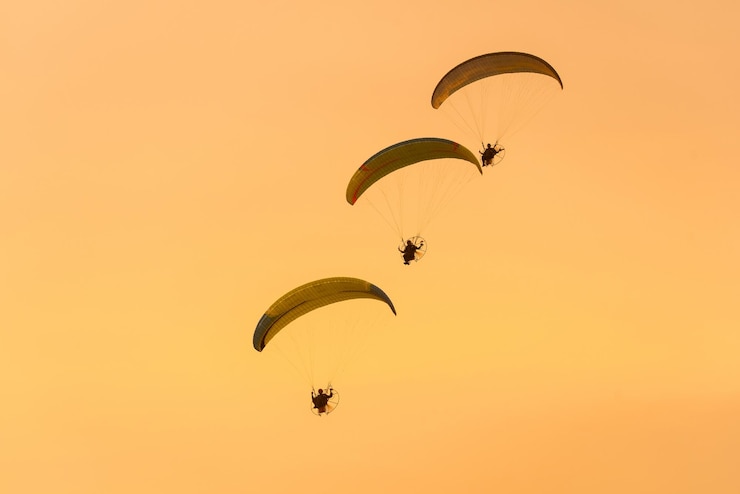Photo vue à bas angle de personnes en parapente contre le ciel au coucher du soleil