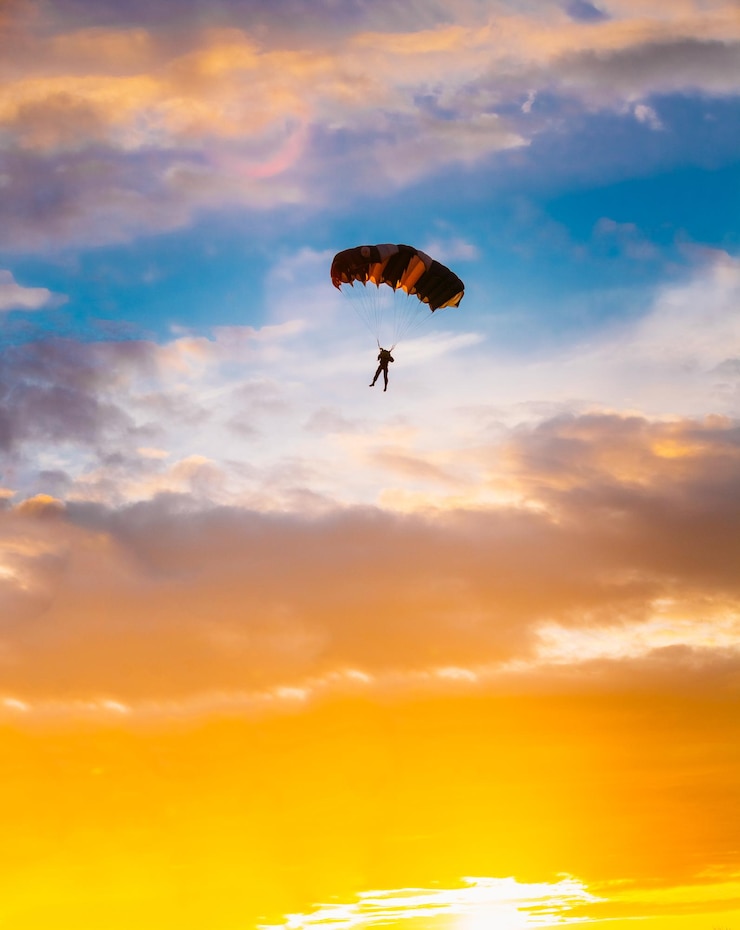 Photo vue à bas angle de la silhouette d'une personne en parapente contre un ciel orange