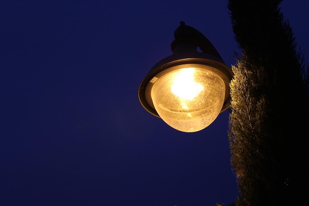 Vue à bas angle de l'usine et de la lampe éclairée contre un ciel bleu clair