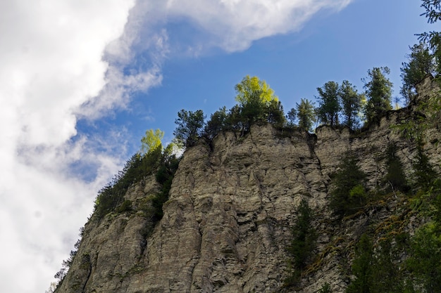 Vue de bas en haut sur des falaises rocheuses calcaires boisées escarpées contre le ciel