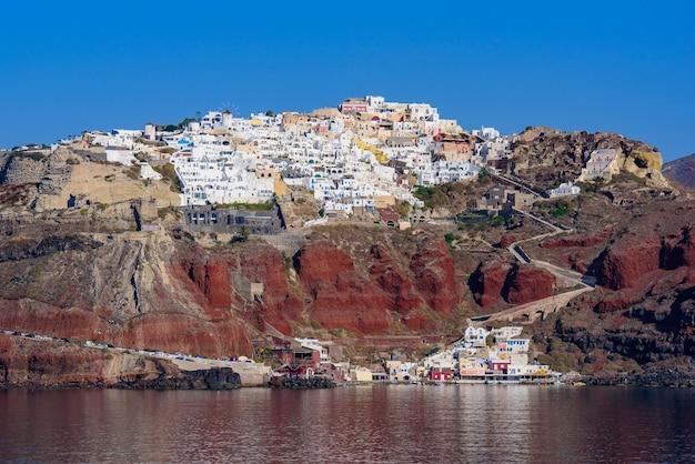 Photo vue sur les bâtiments blancs du village d'oia depuis la mer égée santorini grèce