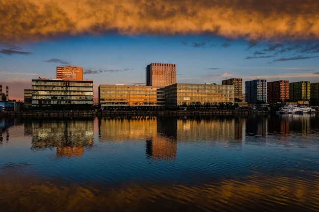 Vue des bâtiments modernes près de l'eau pendant le coucher du soleil.