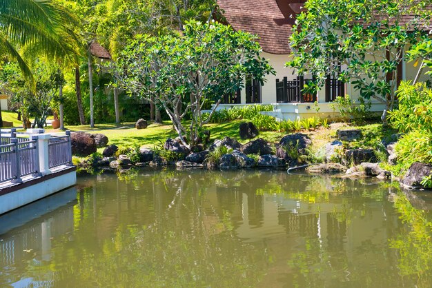 Vue sur le bel étang vert et les bâtiments d'un hôtel de luxe dans un complexe tropical