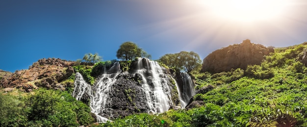 Vue sur la belle cascade de montagne avec un ciel bleu nuageux sur fond