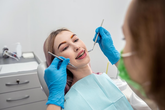 Vue de la bouche d'une femme souriante pendant le traitement dans une clinique dentaire par une femme dentiste