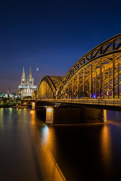 Une vue sur la cathédrale de Cologne et le pont Hohenzollern la nuit avec la lune en Allemagne. Pris à l'extérieur avec une marque 5D III.