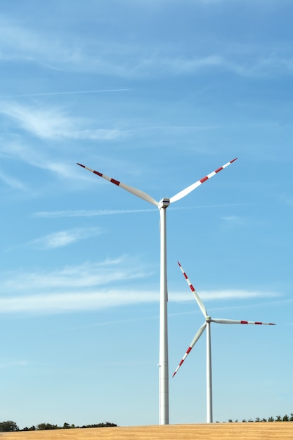 Vue d'une centrale éolienne sur un fond de ciel bleu et de champs de céréales.