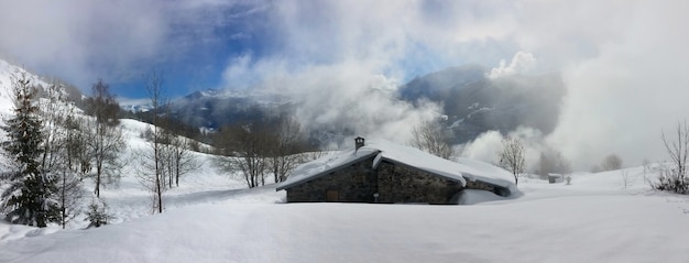 Vue sur chalet alpin dans un paysage de montagne enneigé et ciel nuageux