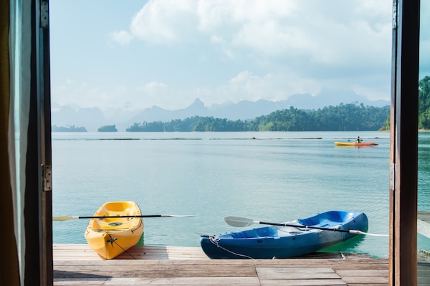 Vue de la chambre avec fenêtre et kayak sur un lac et une montagne.