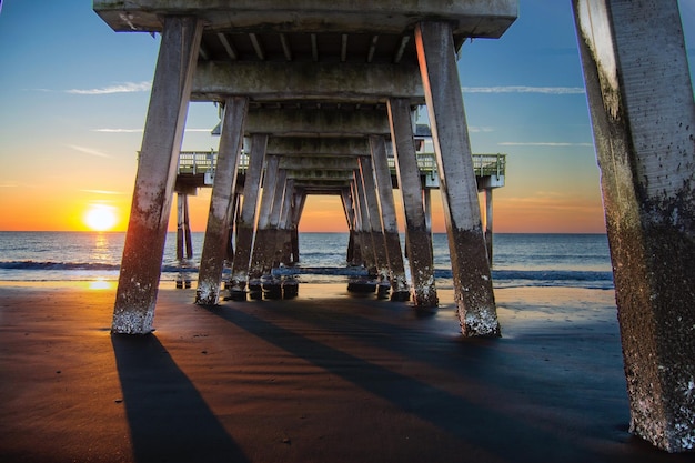 Photo vue ci-dessous de la jetée sur le rivage à la plage au coucher du soleil