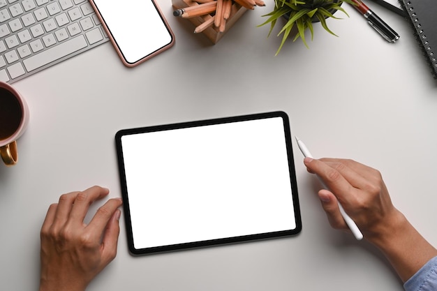 Vue ci-dessus d'un concepteur d'homme tenant un stylet et travaillant avec une table numérique au bureau blanc.