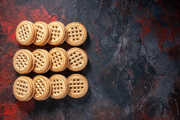 Vue ci-dessus de délicieux biscuits au sucre posés côte à côte sur trois rangées sur le côté droit sur fond de couleurs mélangées avec espace libre