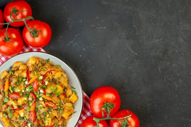 Vue ci-dessus d'un délicieux repas sur une serviette dénudée rouge et des tomates fraîches avec des tiges sur le côté droit sur fond noir