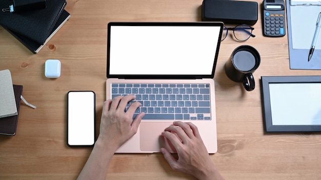 Vue ci-dessus de l'homme travaillant avec un ordinateur portable sur un bureau en bois.