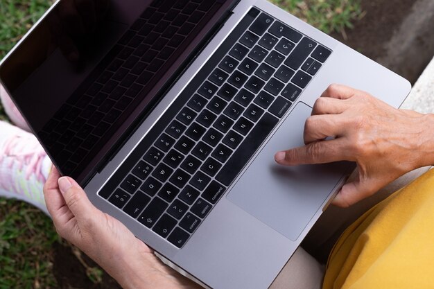 Vue ci-dessus des mains de la femme lors de la frappe sur un ordinateur à clavier. Utilisation d'un ordinateur portable à l'extérieur. Les nomades en voyage
