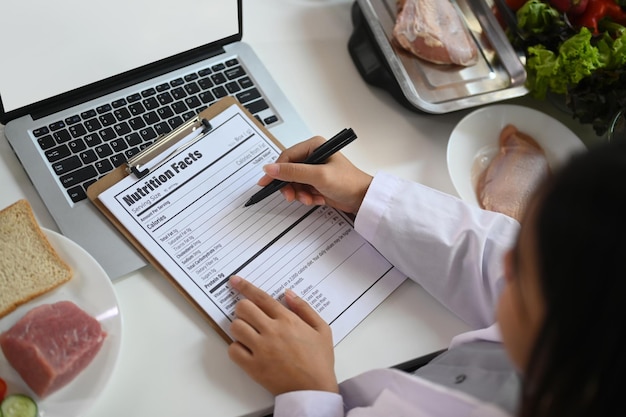 Photo vue ci-dessus de la nutritionniste travaillant dans son bureau divers produits sains concept d'alimentation et de nutrition saines