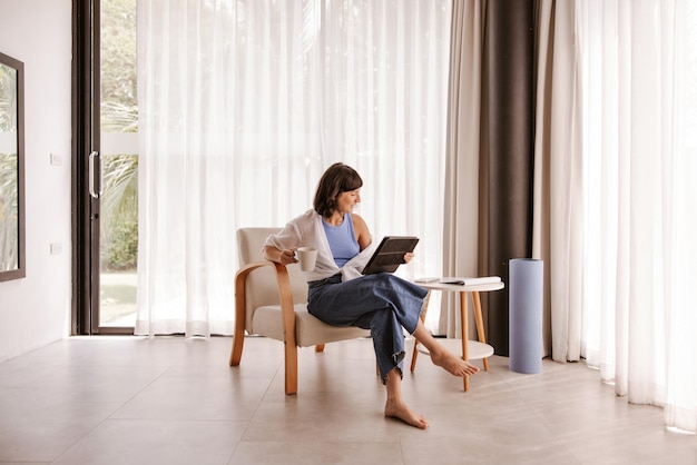 Vue complète d'une femme caucasienne assise sur une chaise regardant un ordinateur portable et souriant