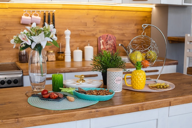Vue sur un comptoir en bois avec des collations, des fleurs de lys, des fruits frais dans un panier, une théière et un plateau d'œufs pour la célébration de Pâques.