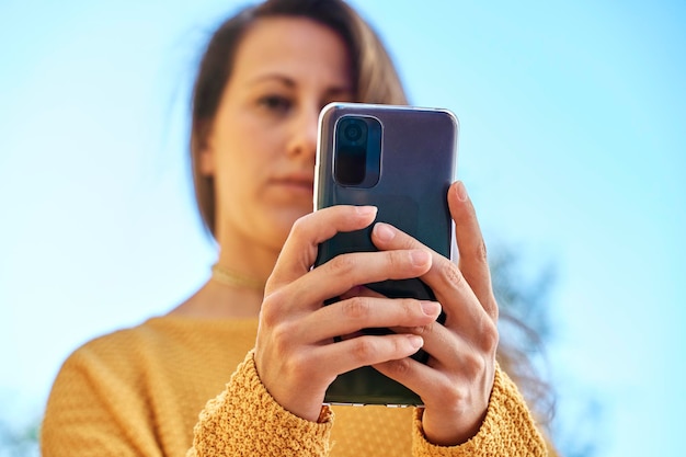 Vue en contre-plongée d'une fille discutant sur son smartphone mise au point sélective sur smartphone