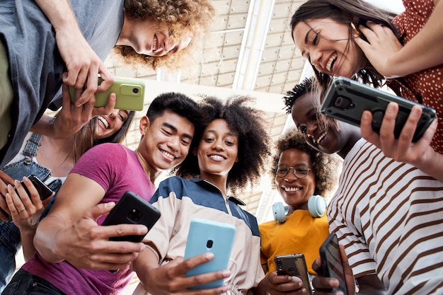 Photo vue en contre-plongée d'un groupe de jeunes adolescents tenant des téléphones portables concept de connexion technologique