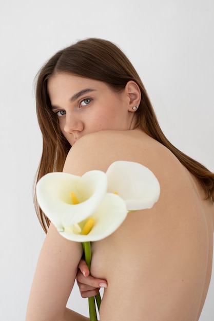 Vue de côté femme posant nue avec des fleurs