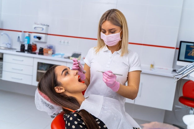 Vue de côté sur une jeune femme dentiste avec des instruments de dentiste dans les mains Le médecin traite les dents des patients dans une clinique moderne