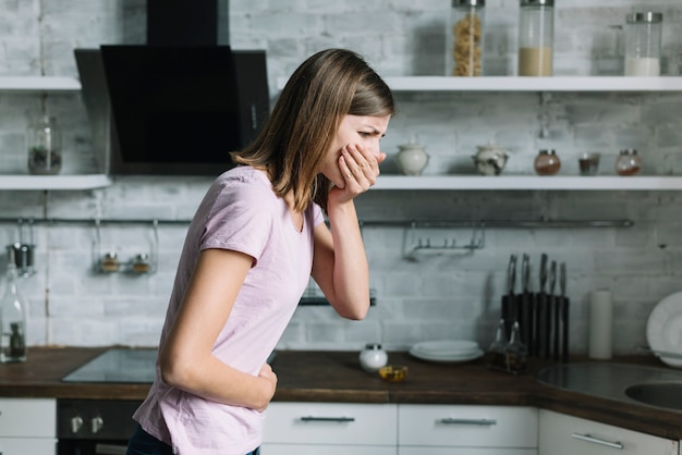 Photo vue de côté d'une jeune femme souffrant de nausée en cuisine