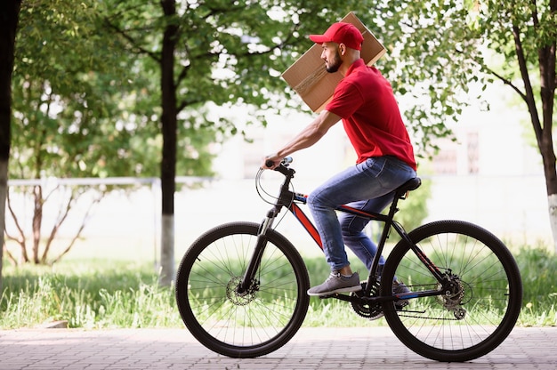 Photo vue côté, jeune homme, livrer colis, sur, a, vélo