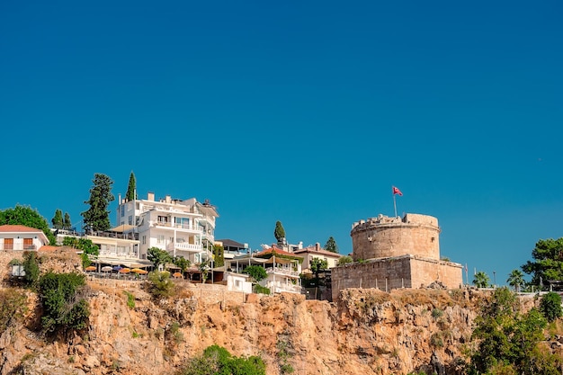 Vue sur la côte rocheuse avec une tour et des bâtiments modernes depuis la mer dans la ville d'Antalya